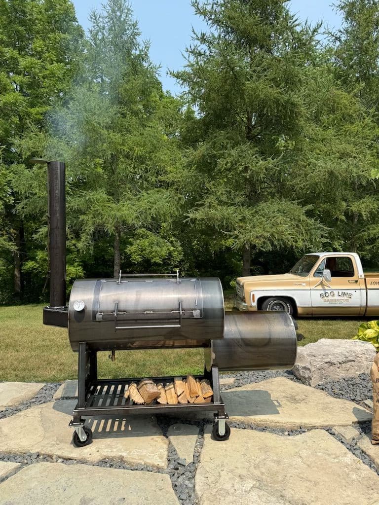 Side view of the Bog Line Small Block 94-gallon offset smoker on a stone patio