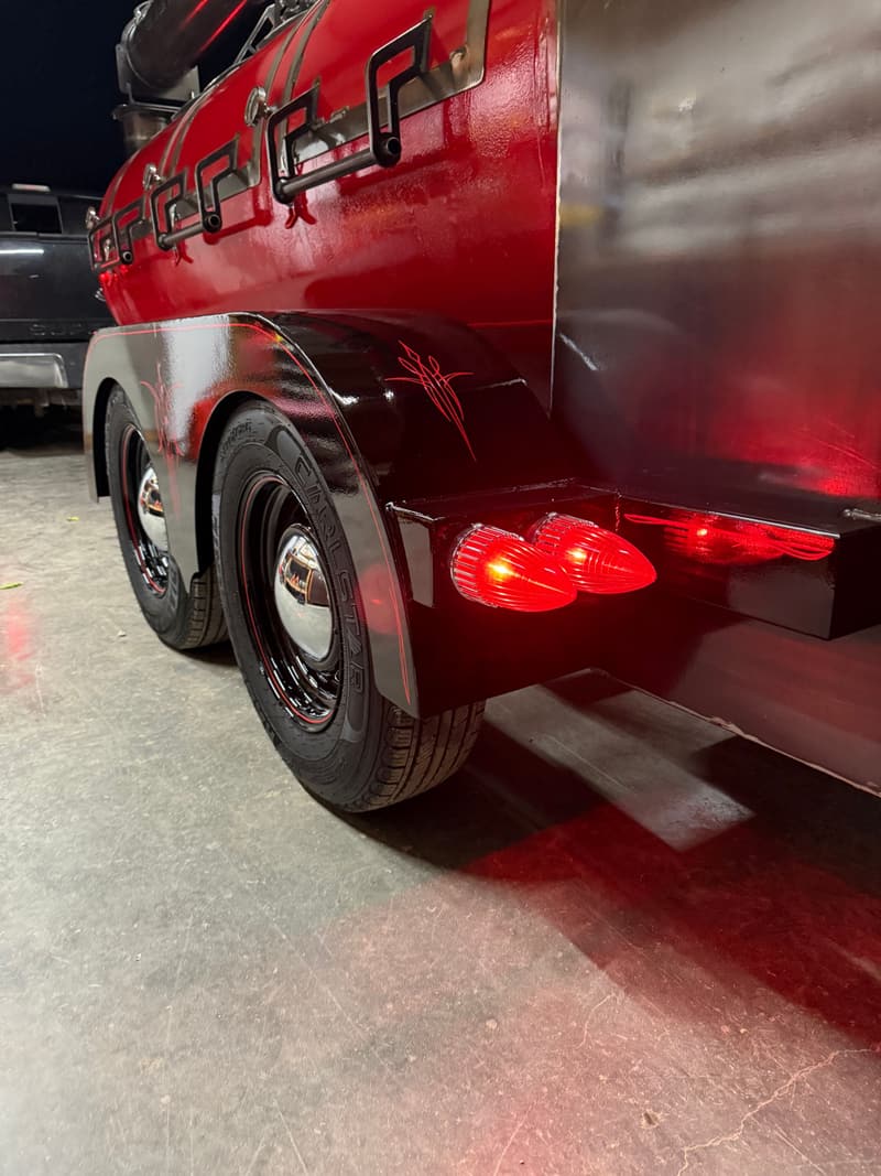 Close-up of a red smoker trailer's 1959 Cadillac-style tail lights, fenders and smoothie wheels